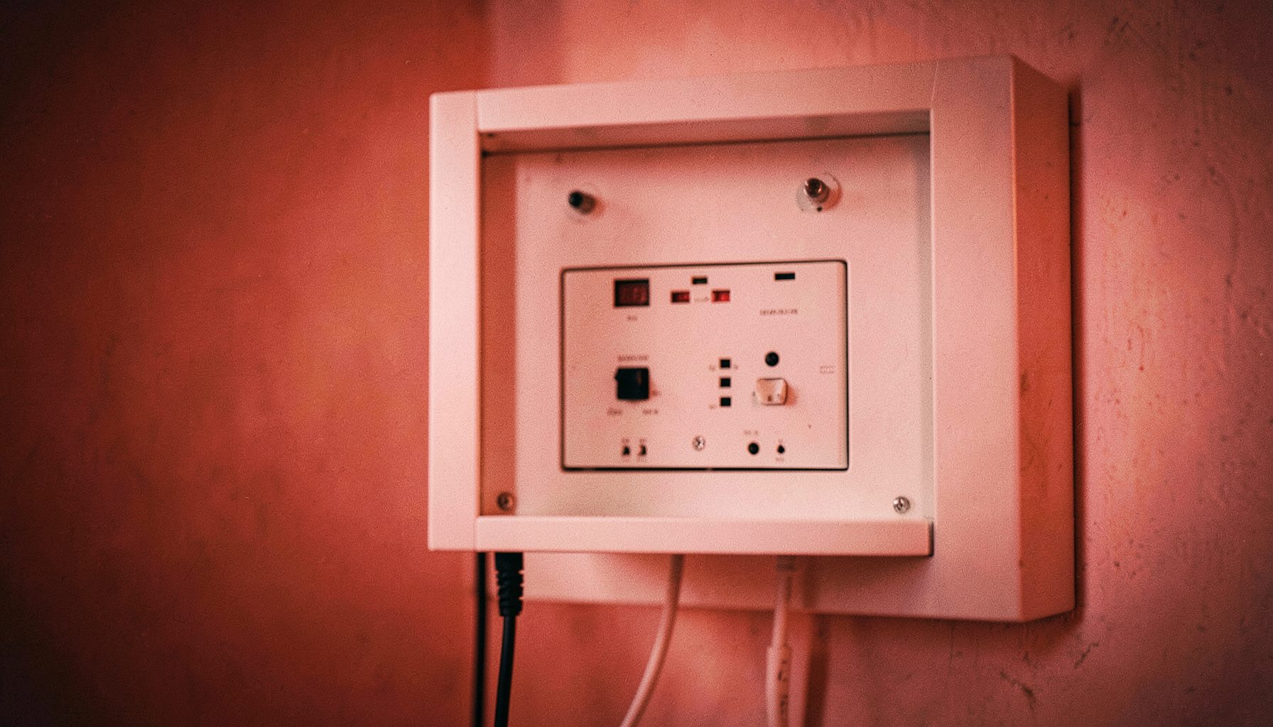 Coffret de communication blanc encastré dans une cloison, avec panneau de brassage et cordons réseau visibles