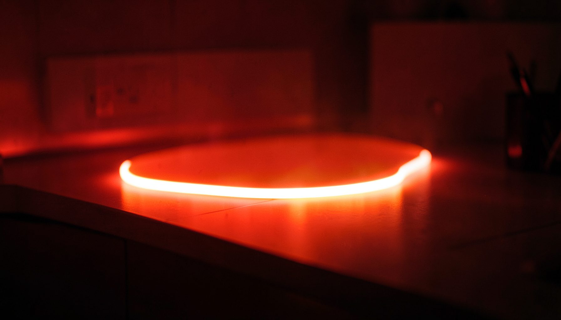 Ruban LED diffusant une lumière chaude le long d'un plan de travail contemporain, ambiance tamisée et design épuré