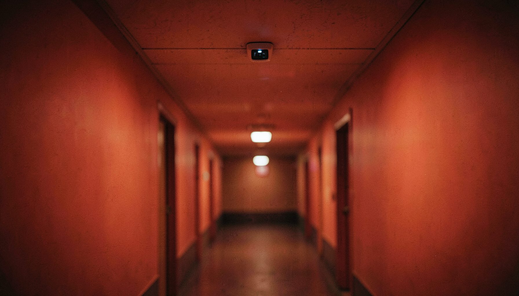 Détecteur de mouvement discret fixé au plafond d'un couloir, lumière ambiante tamisée