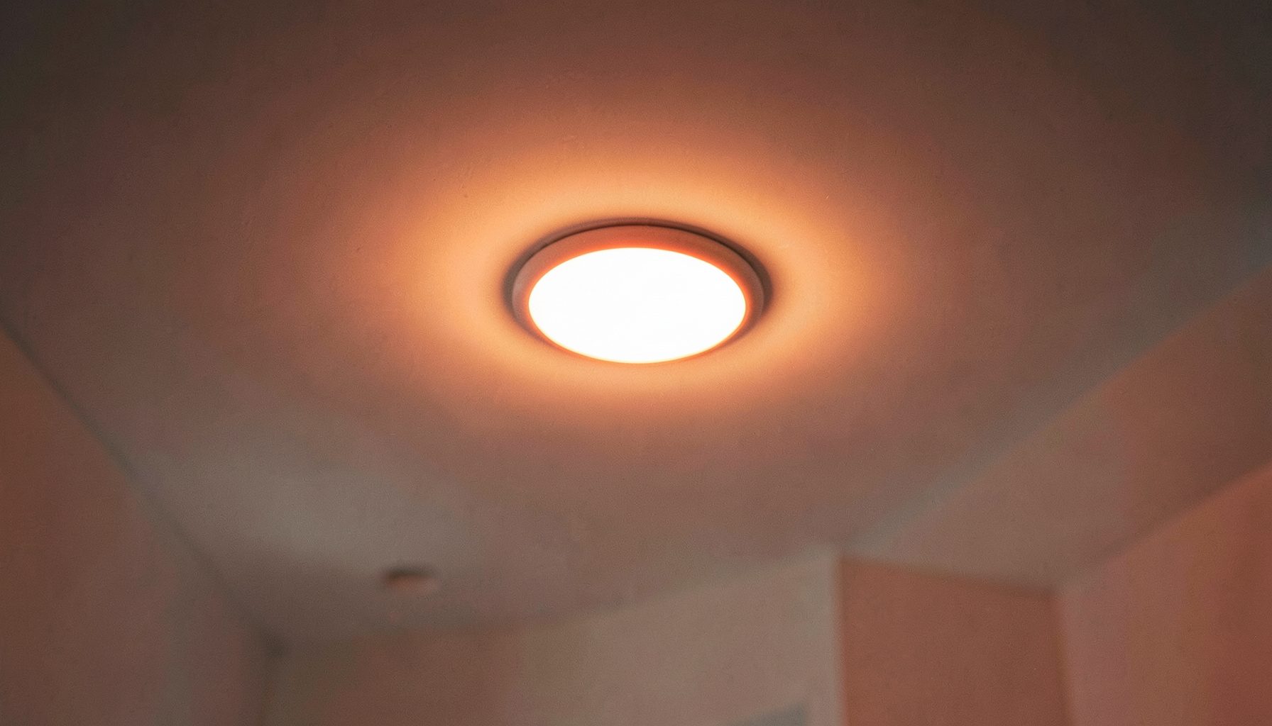 Spot LED encastré allumé dans un plafond blanc, halo lumineux chaud, ambiance épurée et moderne