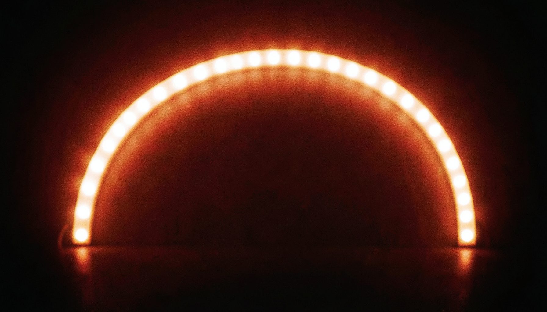 Ruban LED lumineux blanc chaud posé en arc de cercle sur fond sombre, ambiance feutrée et chaleureuse